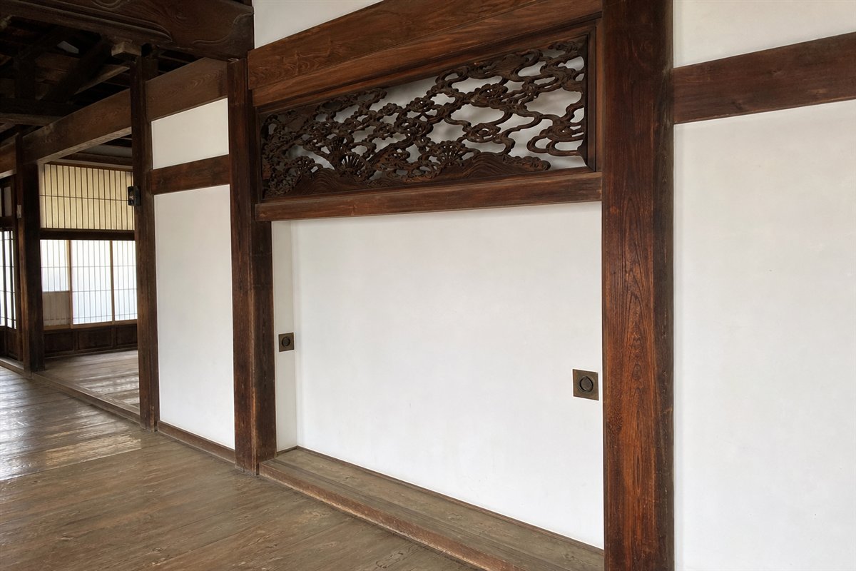 引き戸は撤去され白い漆喰壁になったが、彫刻欄間、鴨居、敷居、二つの引手金物が元の位置に残る。