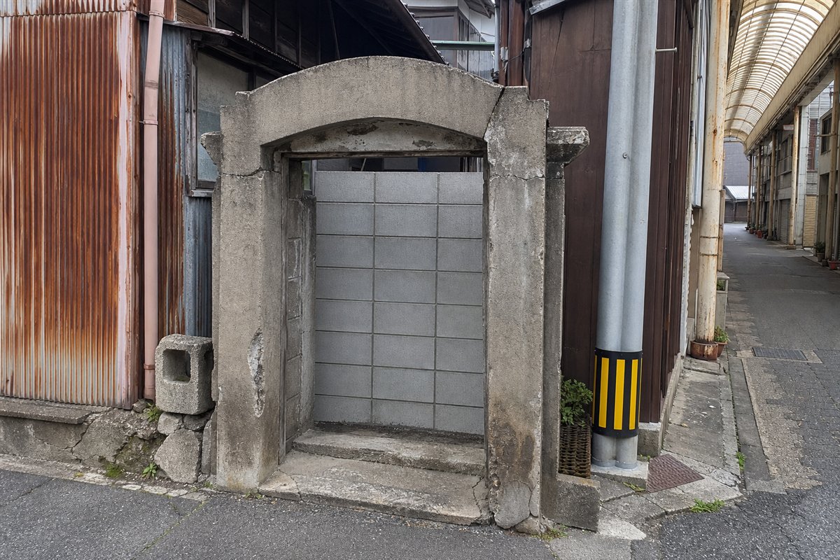 路地入口だった小さなコンクリートアーチの奥が新しいブロック壁で塞がれ、枠だけが保存されている