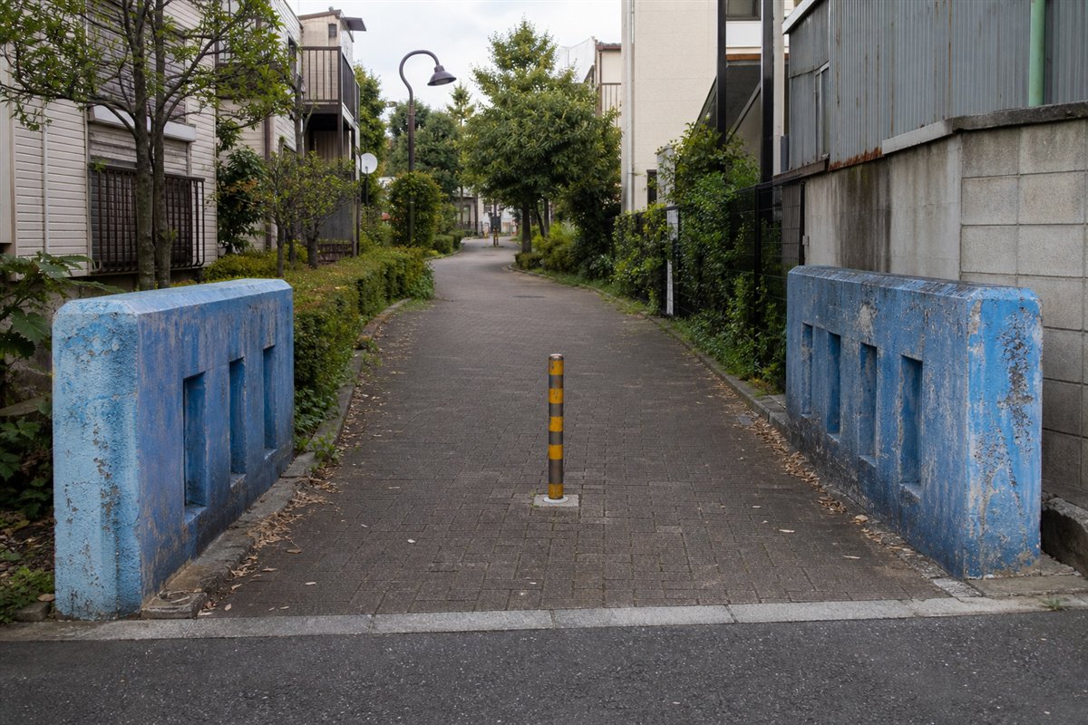 水路は暗渠化され平らな舗装路なのに、向かい合う古い青色の橋欄干だけが残っている