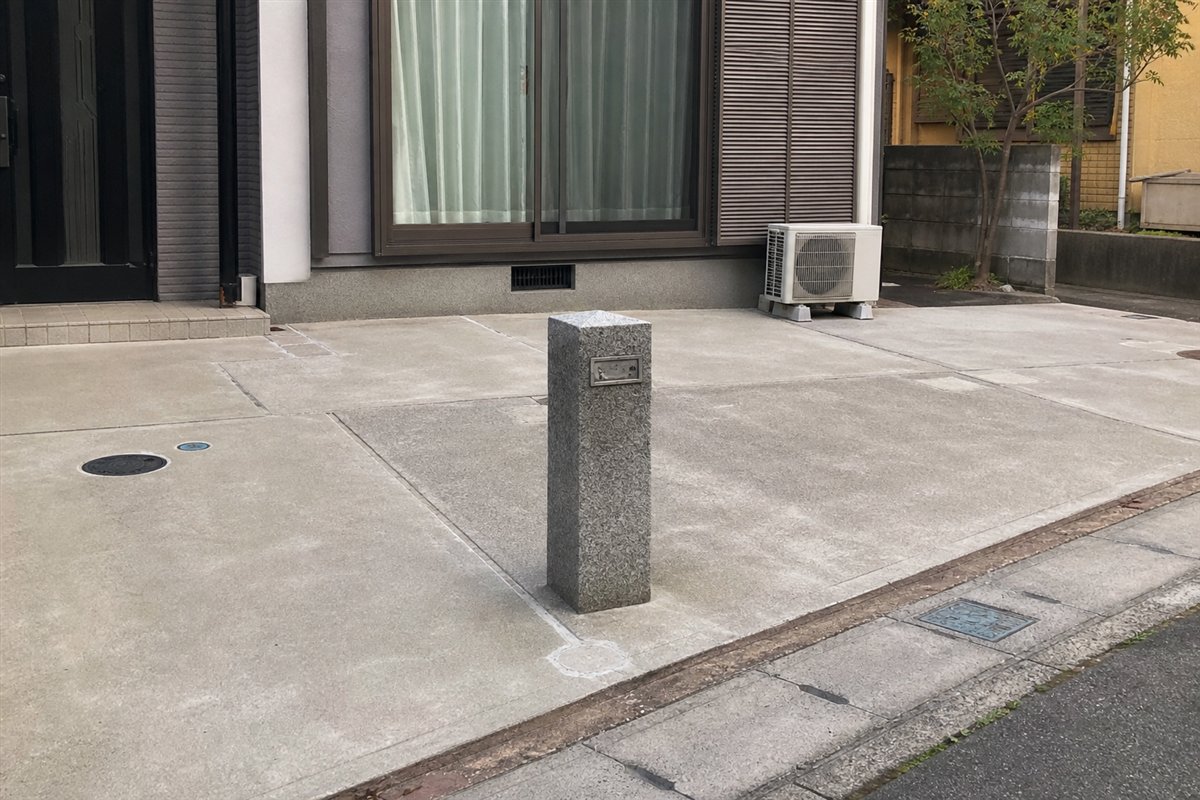 旧門柱の低い石の台座と無記名の表札枠だけが、広くなった舗装面の途中にぽつんと残る